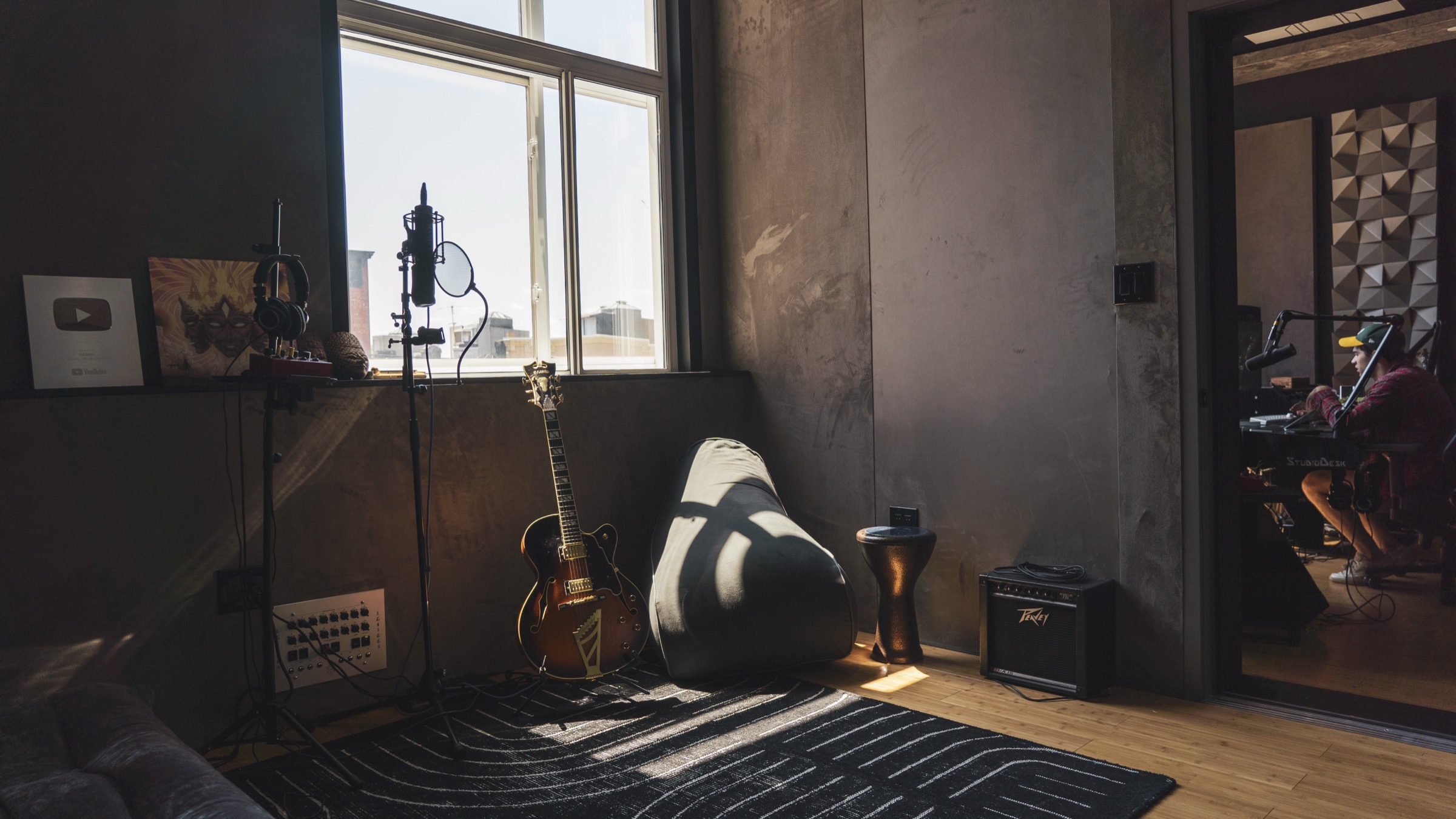 The lounge corner at Antenna Studios — the window, an archtop guitar and the couch in afternoon light
